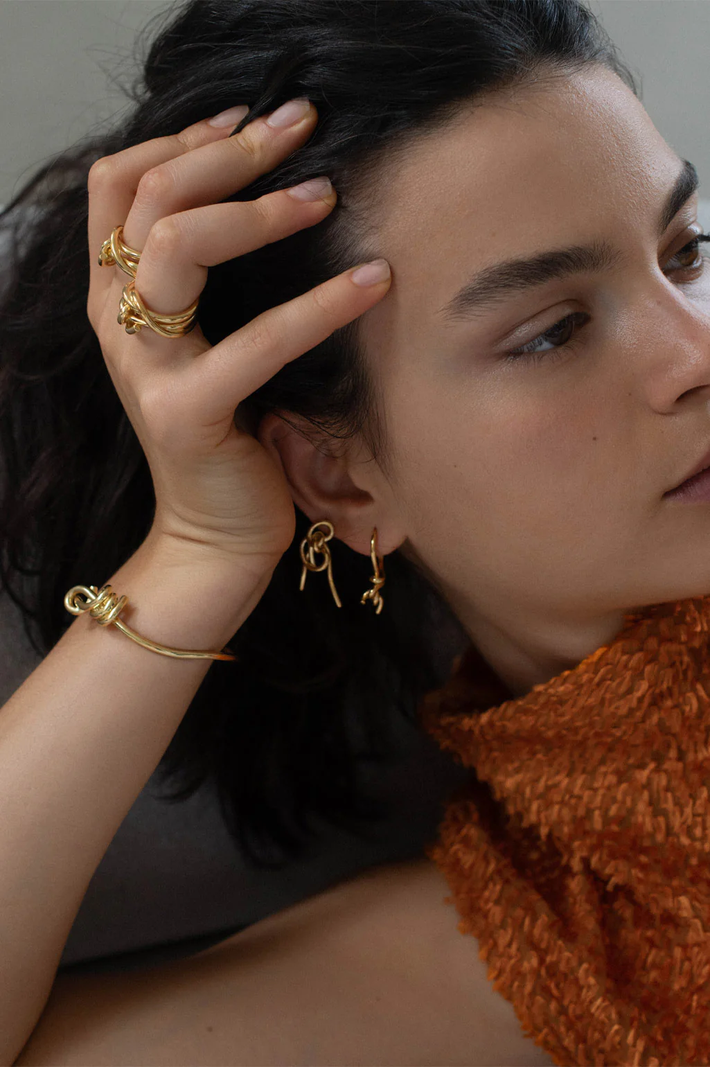 Completedworks delicately knotted bracelet in 18ct yellow gold plating, designed to glide gracefully around the wrist.