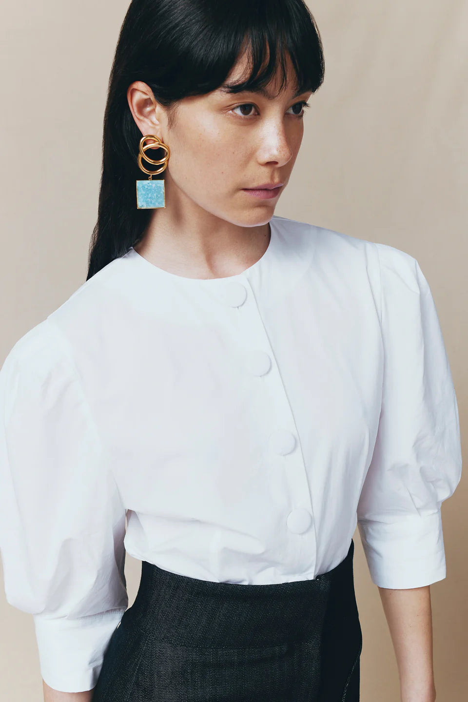 Bold gold earrings with sculptural rings and square blue turquoise drop pendant