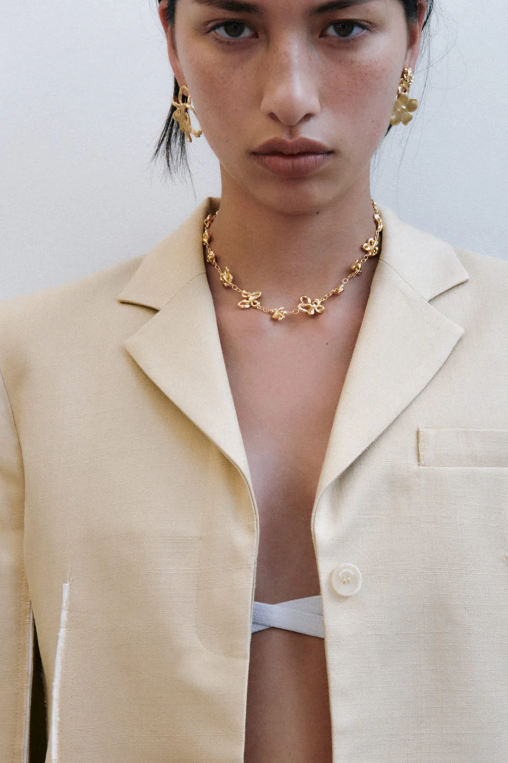 Completedworks delicate flower chain necklace plated in 18ct gold, sitting elegantly above the collarbone.