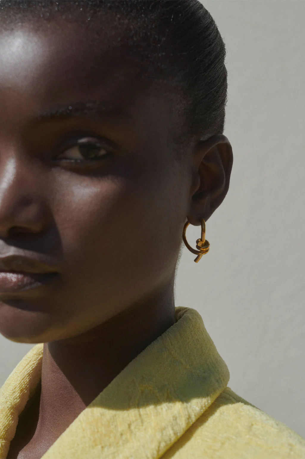 Elegant twisting gold-plated silver hoop earrings by Completedworks, designed with a fluid and modern aesthetic.