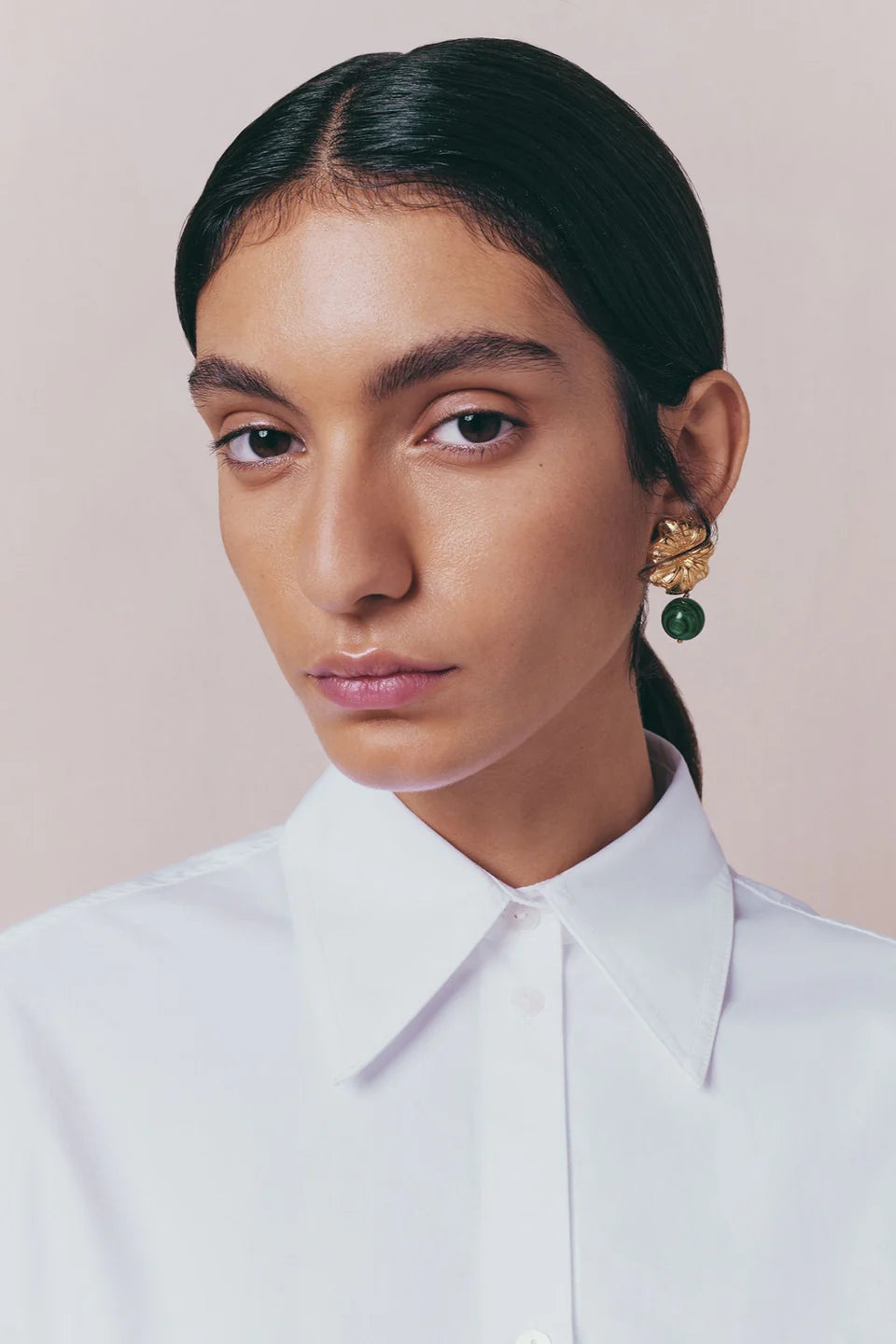 Bold gold earrings with sculpted flower design and green malachite drop stone