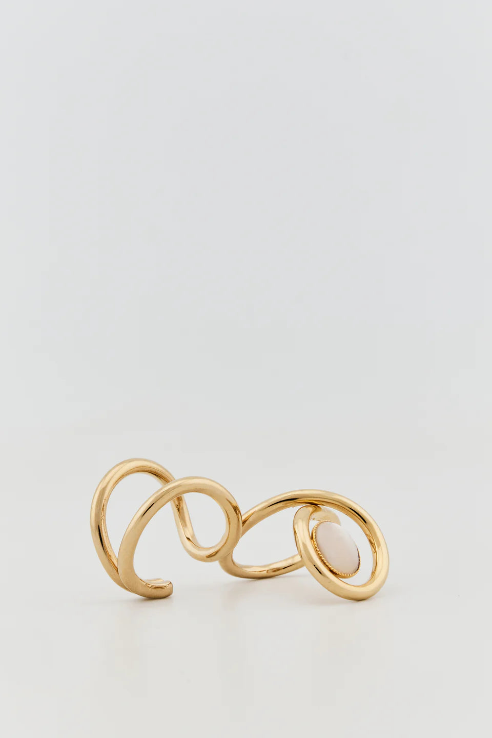 Gold plated double ring with interlocking bands and oval white stone worn on two fingers